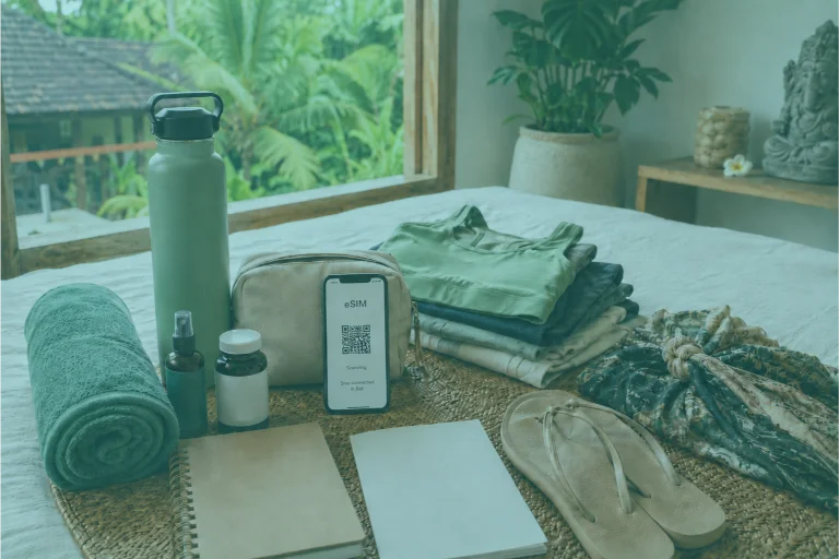 Yoga teacher training packing essentials arranged in a bright Bali villa room with activewear, towel, water bottle, journal, sandals, sarong, toiletries, and eSIM phone.