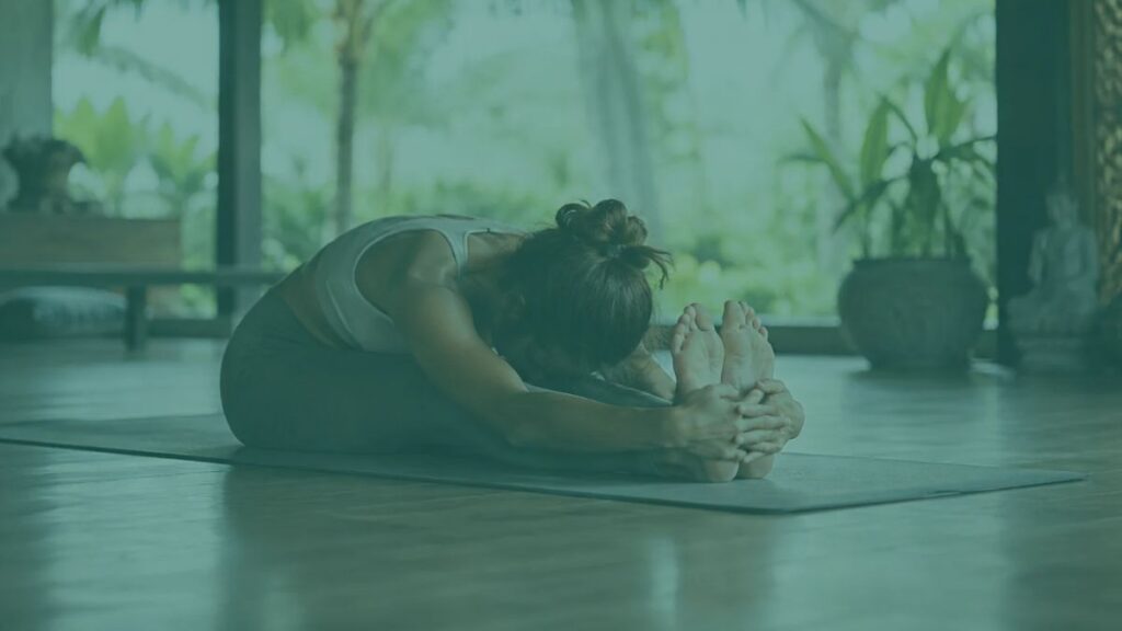 Yoga student holding a long, seated forward fold during a yin yoga teacher training session in Bali.